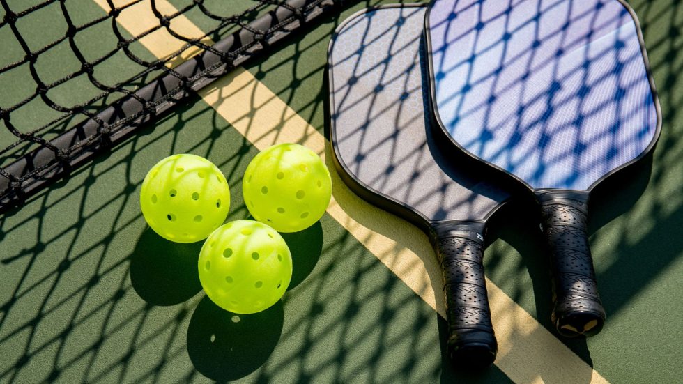 A set of pickleball paddles and balls on a court.